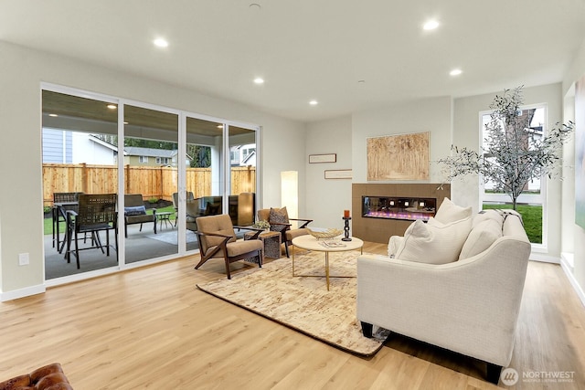 living area with recessed lighting, a tile fireplace, baseboards, and wood finished floors