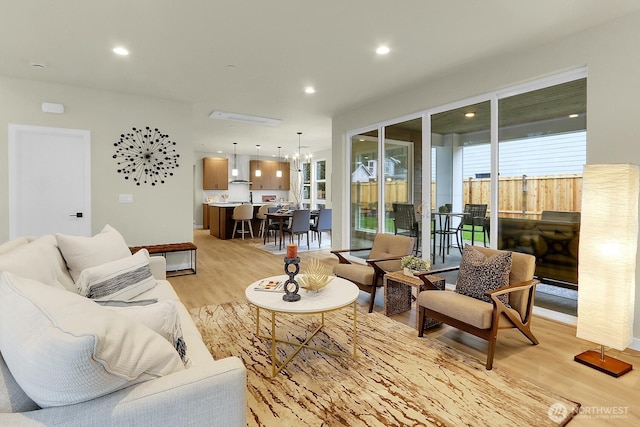 living area with recessed lighting, a notable chandelier, and light wood finished floors