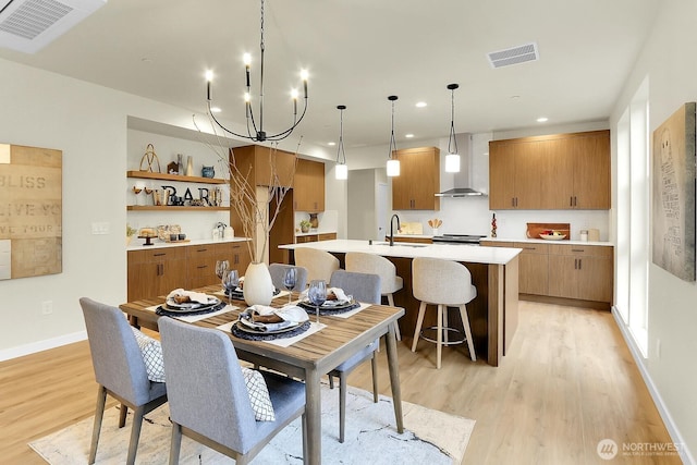 dining room with baseboards, visible vents, light wood finished floors, and an inviting chandelier