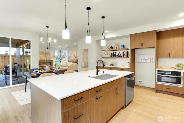 kitchen featuring light wood finished floors, stainless steel appliances, light countertops, open shelves, and a sink