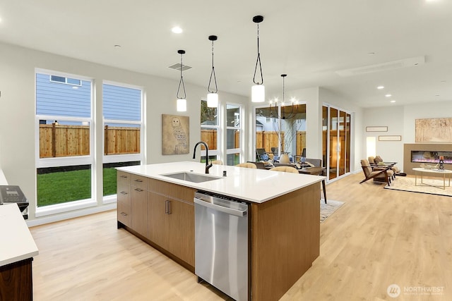 kitchen featuring visible vents, an island with sink, open floor plan, stainless steel dishwasher, and a sink