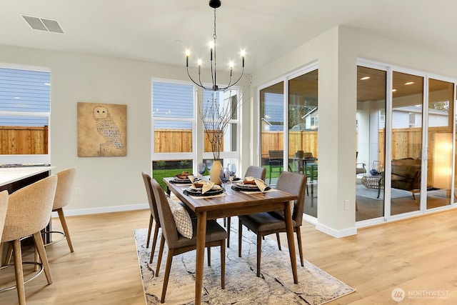 dining area with a chandelier, light wood-type flooring, visible vents, and baseboards