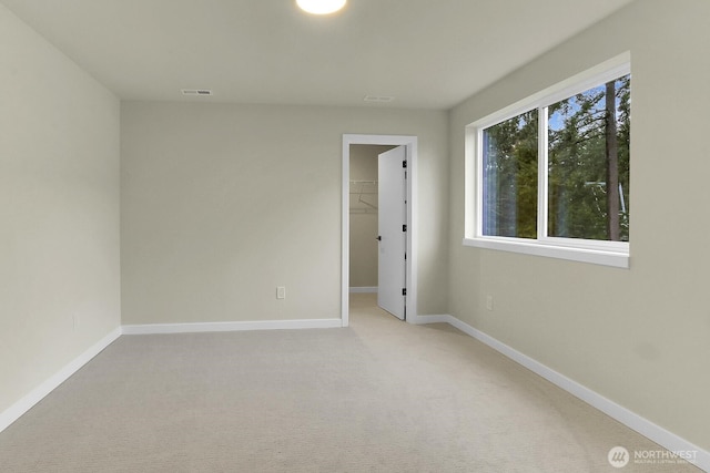 empty room with light carpet, visible vents, and baseboards