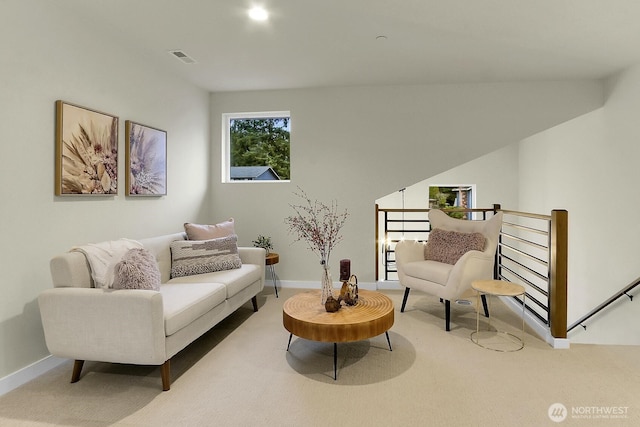 living area featuring carpet, baseboards, visible vents, and an upstairs landing