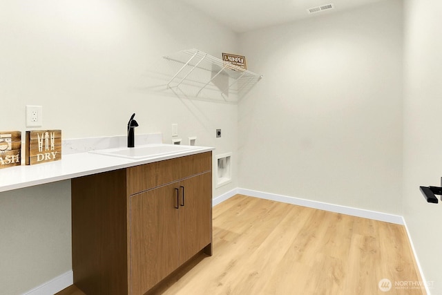 laundry area featuring baseboards, visible vents, hookup for an electric dryer, light wood-type flooring, and a sink