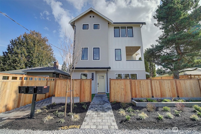 view of front of property with board and batten siding, fence, and a garden