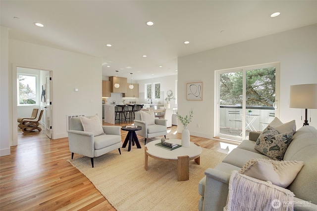 living room with baseboards, light wood-type flooring, and recessed lighting