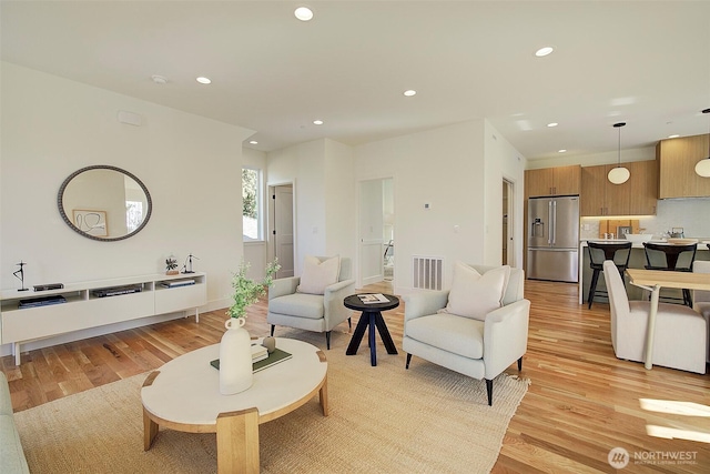 living room with light wood-style floors, visible vents, and recessed lighting