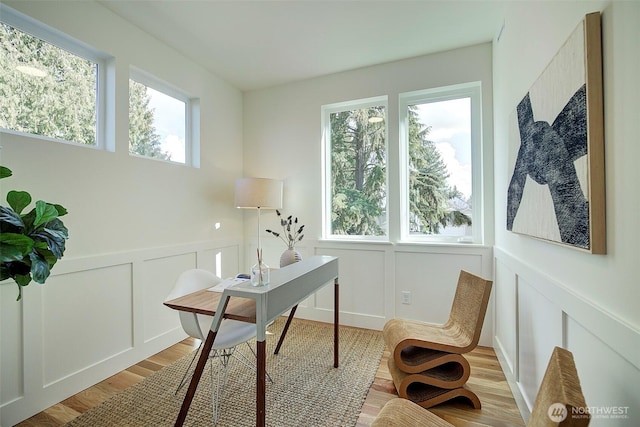 office space with a wainscoted wall, light wood-type flooring, and a decorative wall