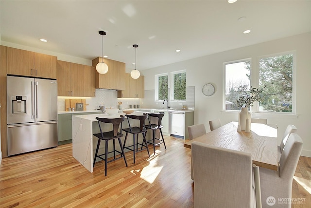 kitchen featuring tasteful backsplash, a breakfast bar, a center island, stainless steel appliances, and light countertops