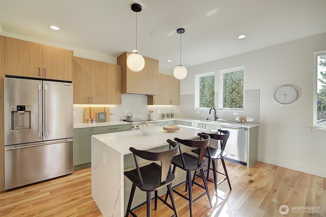 kitchen with stainless steel appliances, light countertops, light wood-style floors, and tasteful backsplash