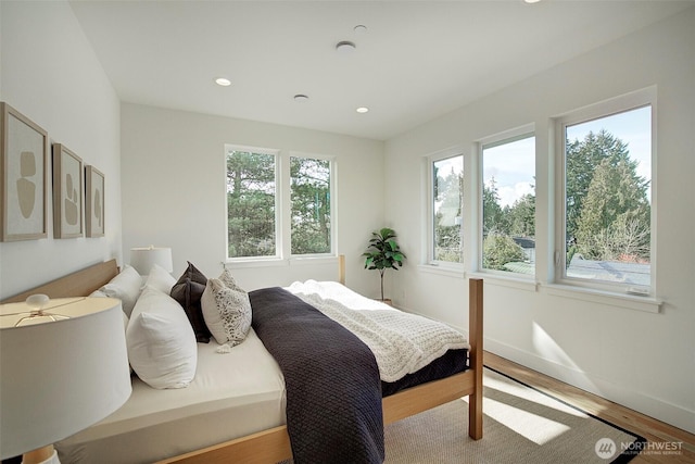 bedroom with recessed lighting, multiple windows, baseboards, and wood finished floors