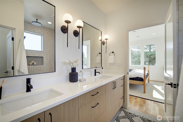 bathroom featuring double vanity, ensuite bathroom, a sink, and wood finished floors