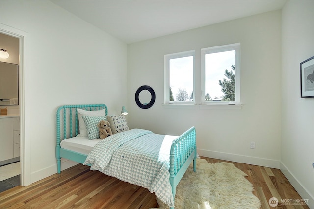 bedroom featuring connected bathroom, baseboards, and wood finished floors