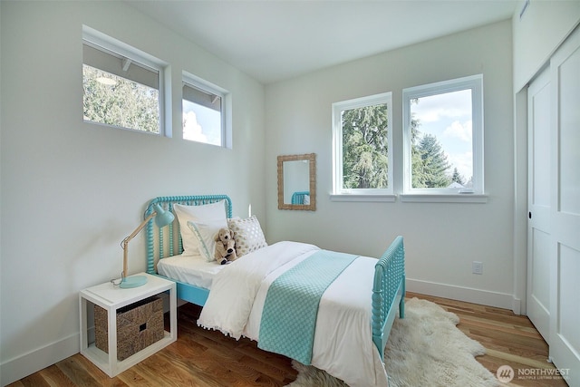 bedroom featuring a closet, baseboards, and wood finished floors