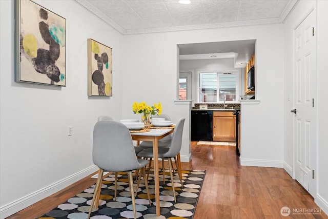 dining area featuring light wood-type flooring, crown molding, and baseboards