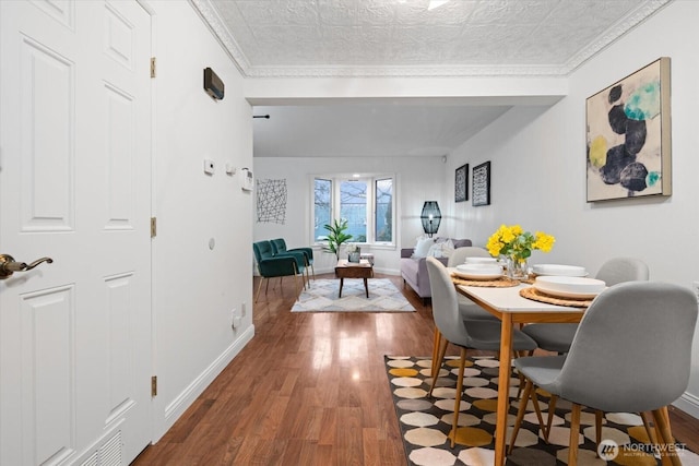 dining space featuring crown molding, dark wood finished floors, an ornate ceiling, and baseboards