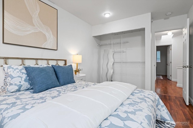 bedroom featuring dark wood-type flooring, a closet, and baseboards