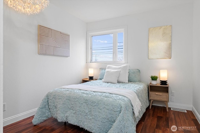 bedroom with dark wood-style floors, visible vents, baseboards, and a notable chandelier