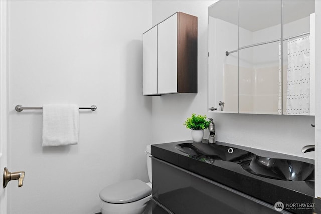 full bathroom featuring a shower with shower curtain, vanity, and toilet