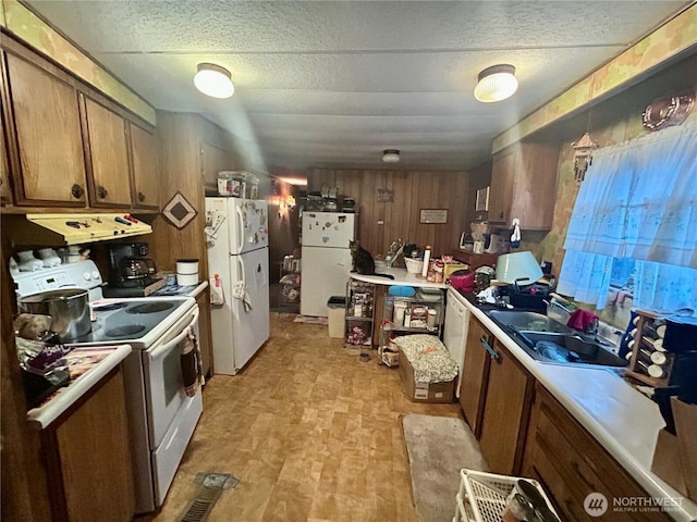 kitchen featuring white appliances, brown cabinets, ventilation hood, light countertops, and a sink