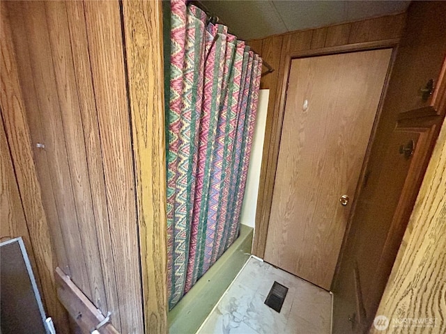 bathroom with wooden walls and shower / bath combo with shower curtain