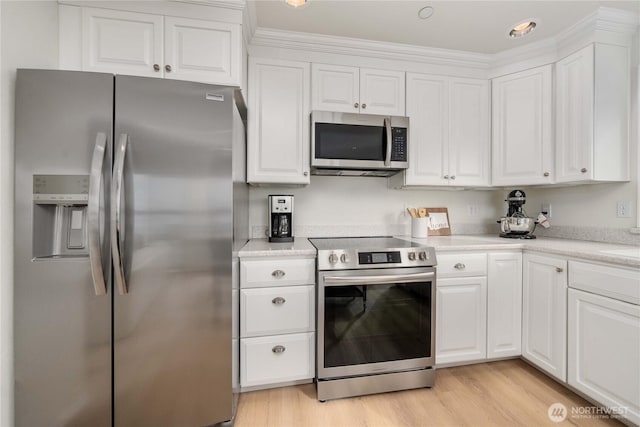 kitchen featuring appliances with stainless steel finishes, white cabinets, light countertops, and light wood finished floors