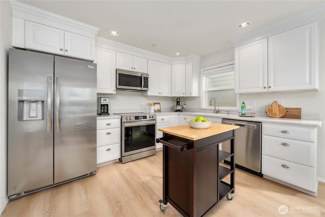 kitchen featuring light wood-style flooring, white cabinetry, stainless steel appliances, and a sink