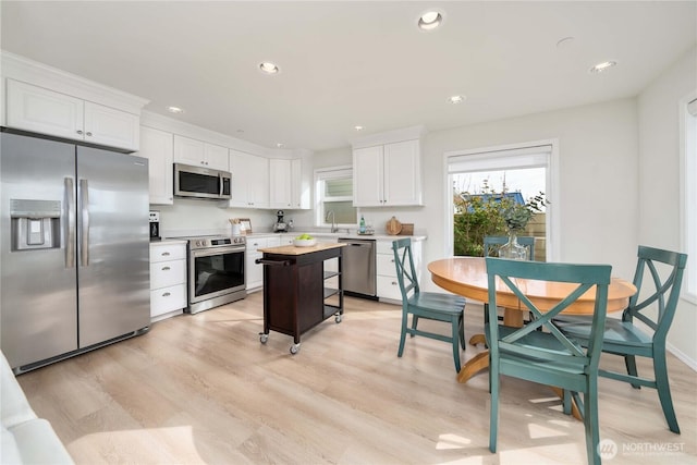 kitchen with recessed lighting, white cabinets, appliances with stainless steel finishes, and light wood-style flooring