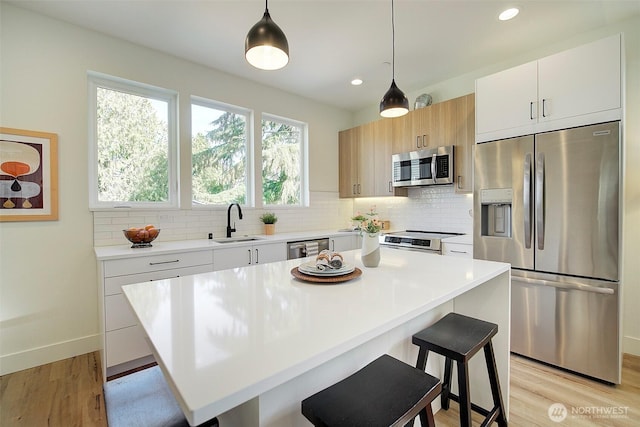 kitchen featuring decorative backsplash, a breakfast bar area, stainless steel appliances, light countertops, and light wood-type flooring