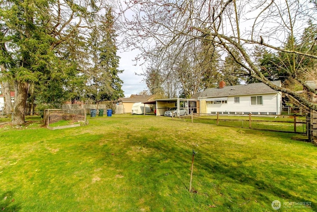 view of yard featuring fence and a carport