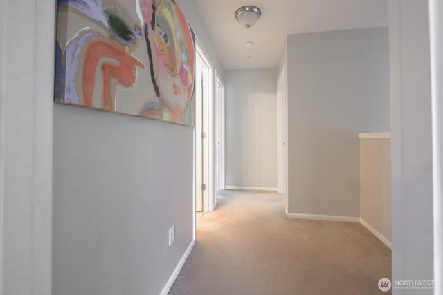 corridor featuring light carpet and baseboards