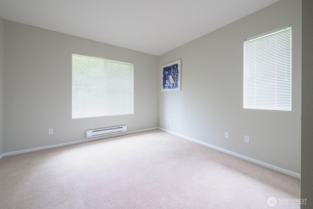 empty room with a healthy amount of sunlight, a baseboard radiator, baseboards, and light colored carpet