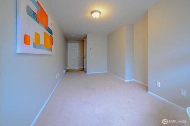 spare room with baseboards and light colored carpet