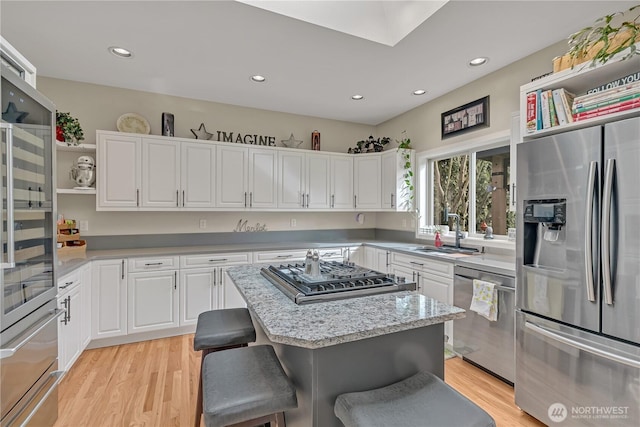 kitchen with white cabinets, appliances with stainless steel finishes, open shelves, and a sink