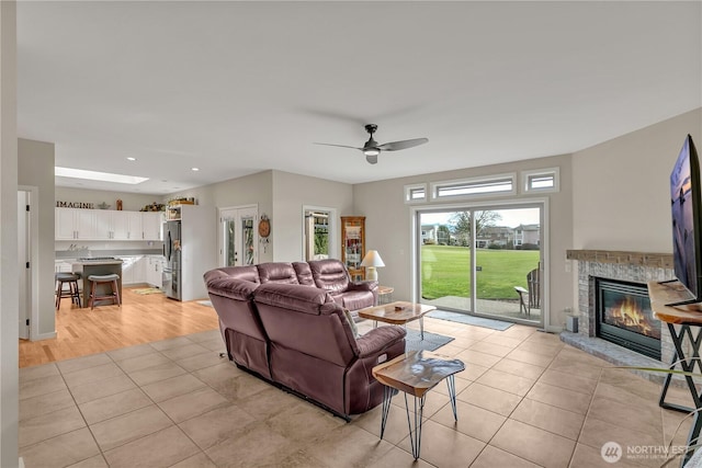 living room featuring recessed lighting, ceiling fan, light tile patterned flooring, and a glass covered fireplace