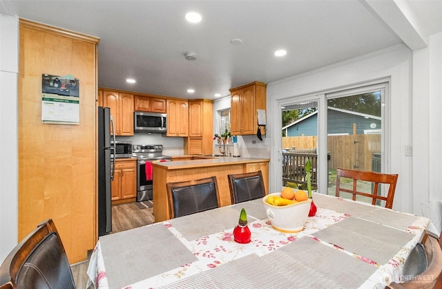 kitchen featuring appliances with stainless steel finishes, a peninsula, light countertops, a sink, and recessed lighting