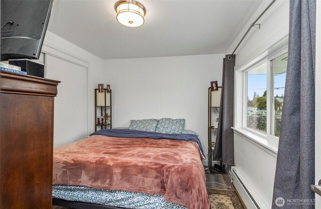 bedroom with a baseboard radiator and wood finished floors