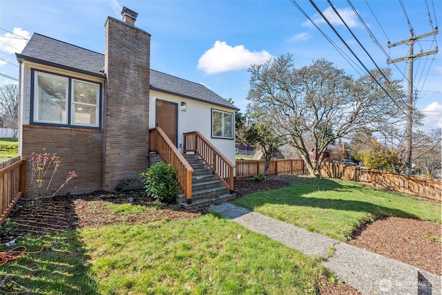 exterior space with fence private yard, a shingled roof, a chimney, and a yard