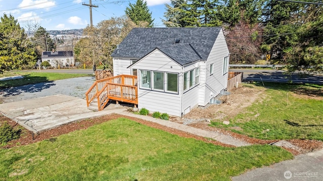 view of front of property with a shingled roof and a front yard