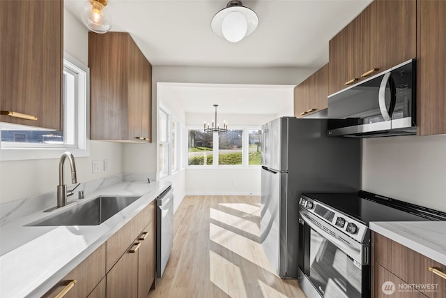 kitchen featuring an inviting chandelier, modern cabinets, appliances with stainless steel finishes, and a sink