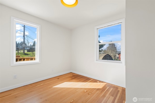 spare room with baseboards and wood finished floors