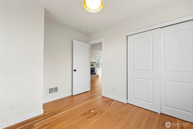 unfurnished bedroom with light wood finished floors, a closet, visible vents, and baseboards