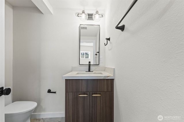 bathroom featuring baseboards, vanity, and toilet