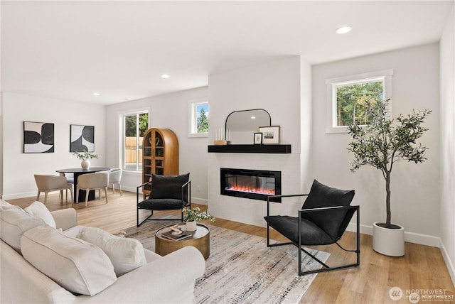 living area featuring a glass covered fireplace, light wood finished floors, and recessed lighting