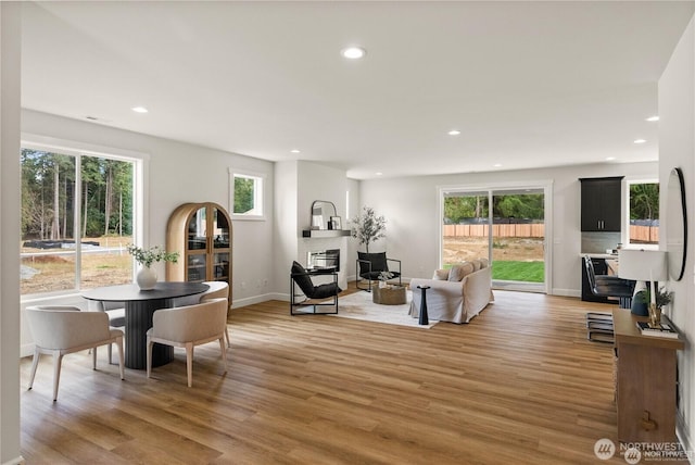 dining room featuring baseboards, a glass covered fireplace, wood finished floors, and recessed lighting