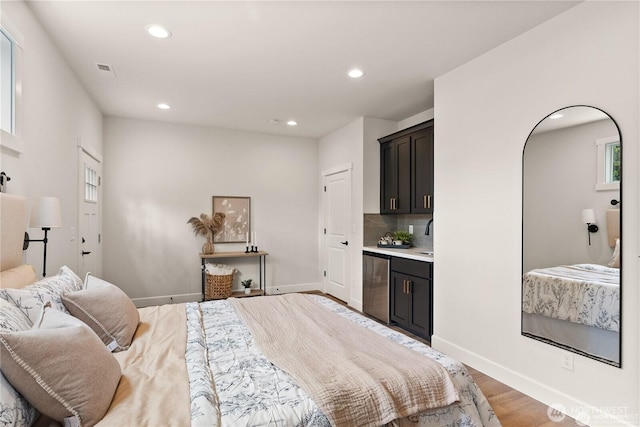 bedroom with baseboards, bar area, wood finished floors, and recessed lighting