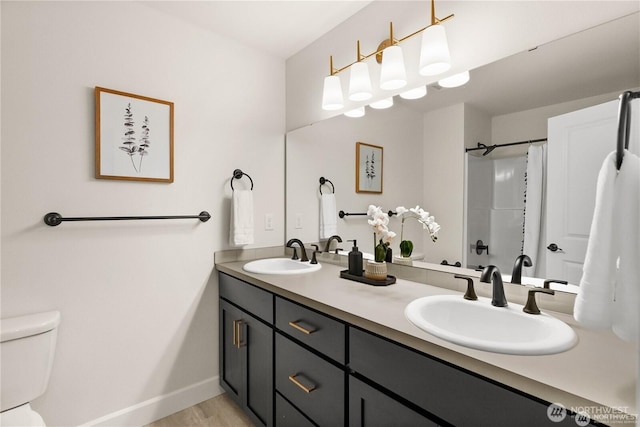 bathroom with double vanity, a sink, toilet, and baseboards