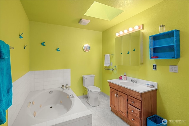 bathroom featuring toilet, a skylight, vanity, and a whirlpool tub