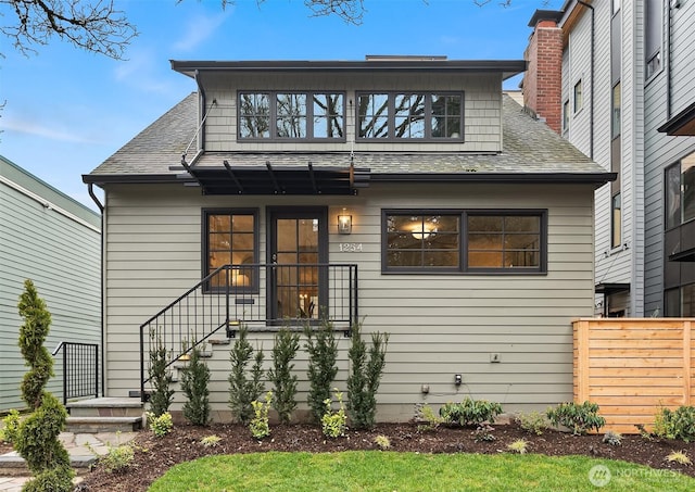 view of front of property featuring roof with shingles, fence, and a chimney